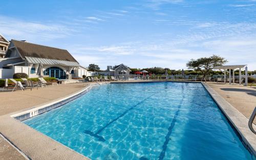 een groot blauw zwembad met stoelen en een gebouw bij Our Tree House by Oversee 30A in Inlet Beach