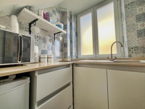 a kitchen with a sink and a microwave at U lettu da zita Acitrezza in Acitrezza
