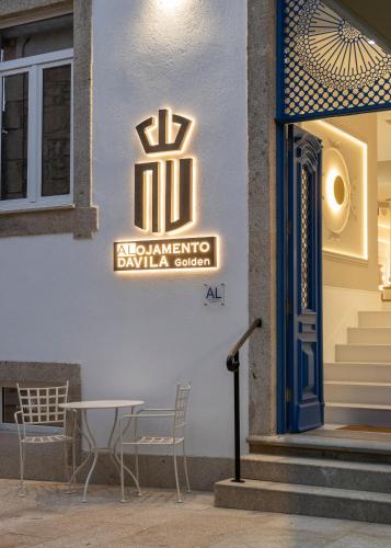a sign on the side of a building with a table and chairs at Alojamento da Vila Golden in Valença