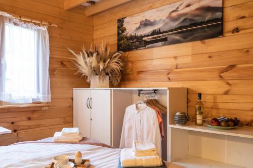 a room with wooden walls and a bed with a cabinet at Domek nad jeziorem Strykowskim in Sapowice