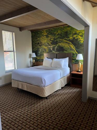 a bedroom with a large bed with a painting on the wall at Northern Queen Inn in Nevada City