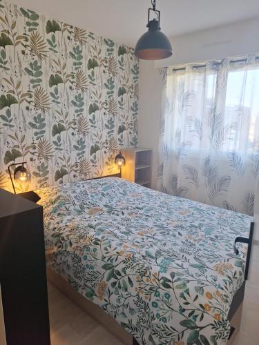 - une chambre avec un lit doté d'un couvre-lit fleuri dans l'établissement Mer et sable, à Cabourg