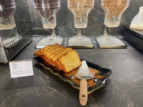 a table with a piece of cake and a plate of bread at Hôtel Beausoleil in Montélimar