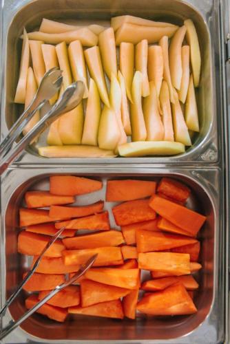 two plastic containers filled with carrots and apples and tongs at Pousada Margerie Ubatuba - Ítagua in Ubatuba
