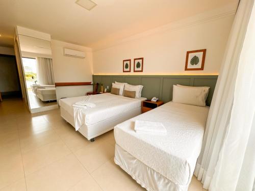 a hotel room with two beds and a bathroom at Hotel Premium Recanto da Passagem in Cabo Frio