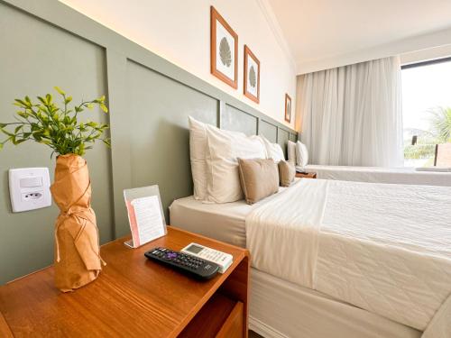 a hotel room with a bed and a remote control on a table at Hotel Premium Recanto da Passagem in Cabo Frio