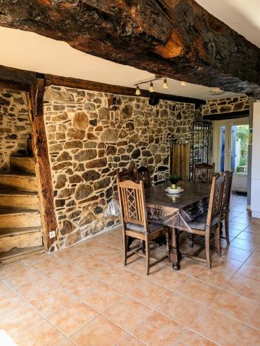 une salle à manger avec un mur en pierre, une table et des chaises dans l'établissement La Barbotierre 10 Personnes en bord de mer, à Cherrueix