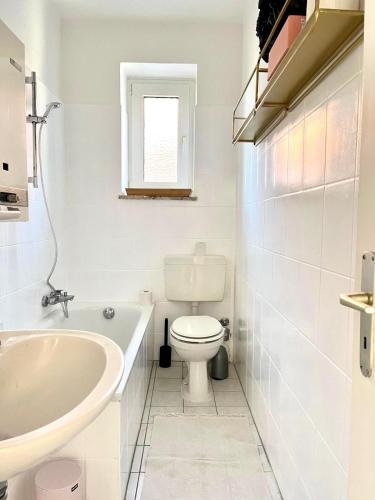 a white bathroom with a toilet and a sink at Modern - ruhig - 20 Min zur Perlebucht! in Heide