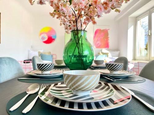 a table with plates and a vase with flowers on it at Modern - ruhig - 20 Min zur Perlebucht! in Heide