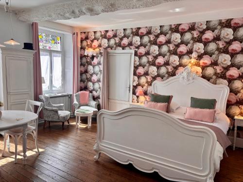 a bedroom with a white bed and a floral wall at La Tannerie de Montreuil in Montreuil-sur-Mer