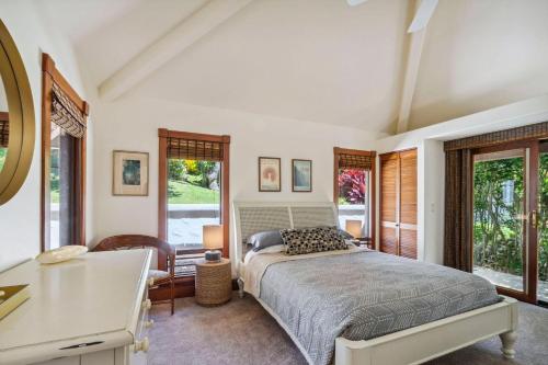 a bedroom with a bed and a desk and windows at Kapiolani - As seen on HGTV in Princeville