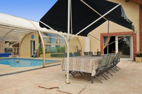 - une table avec des chaises et un parasol à côté de la piscine dans l'établissement Gite de la Loge, à Moussy