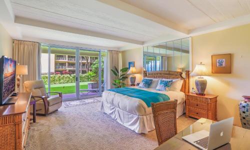 a bedroom with a bed and a desk with a laptop at Whaler 102 in Lahaina