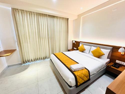 a bedroom with a bed with yellow pillows and a window at Sterling Wood Hotel in Bengaluru