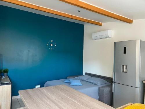 Cette chambre est dotée d'un mur bleu, d'un lit et d'un réfrigérateur. dans l'établissement Valras maison bord de mer, à Sérignan