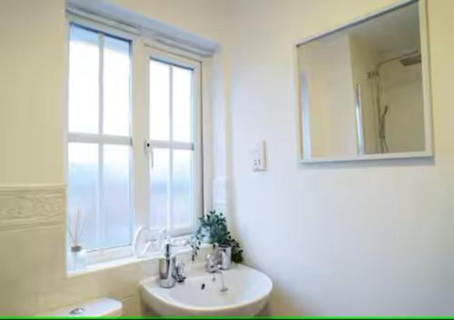 a bathroom with a sink and a mirror and a window at 5 Bedrooms, Sleeps 10, Free Parking, Near NEC & Airport, Contractors in Solihull