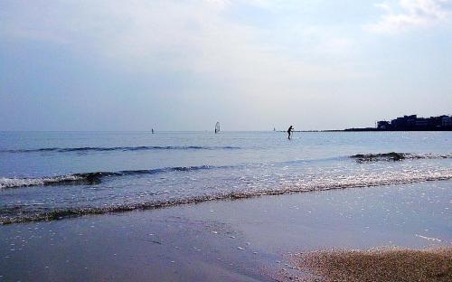 a beach with people in the water and a sail boat at 女性専用 Inn By The Sea Kamakura - Women's Guesthouse in Kamakura