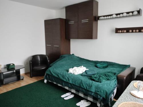 a bedroom with a bed with a green comforter and slippers at AlexHouseTheater in Craiova