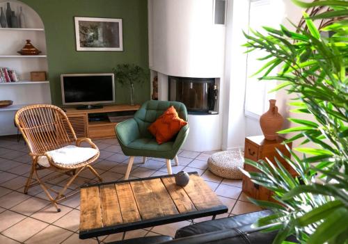a living room with a green chair and a television at La Nuit étoilée - Maison d 'artiste - Auvers-sur-Oise in Auvers-sur-Oise
