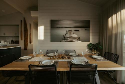 a dining room with a table with chairs and a painting at The Boat House Retreat Squeaking Point in Port Sorell