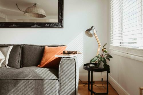 a living room with a gray couch and a lamp at Smiths Cottage Devonport in Devonport