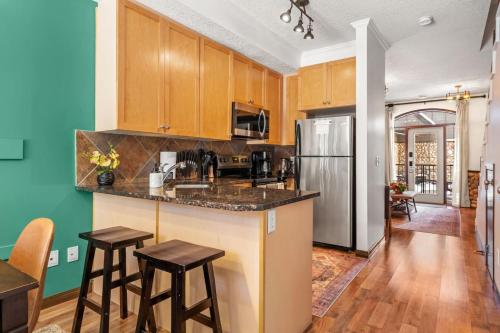 a kitchen with wooden cabinets and a stainless steel refrigerator at 2BR Mystic Springs Escape with BBQ, Pool, Hot tub in Canmore