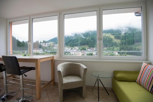 a living room with windows and a couch and a table at Panorama Spa Lodges DasSchiller Superior in Bad Gastein