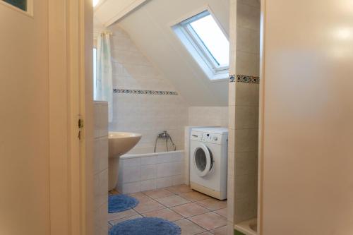 Un baño con lavadora y lavabo. en Een Ruime Vakantiehuis aan de kust in het prachtige Sint Maartenszee, en Sint Maartenszee