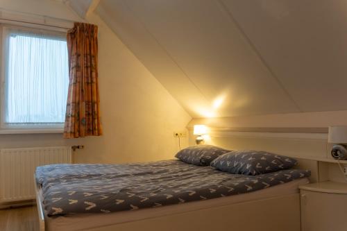 Un dormitorio con una cama con dos almohadas encima. en Een Ruime Vakantiehuis aan de kust in het prachtige Sint Maartenszee, en Sint Maartenszee