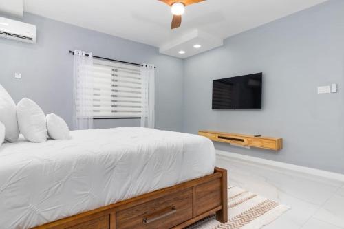 a white bedroom with a bed and a tv at Coastal Escape in Riviera Tower Isle Beach Neaby in St Mary