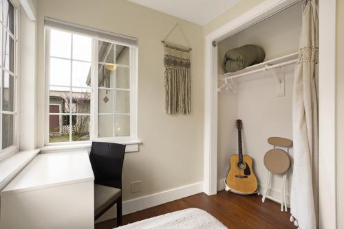 a room with a guitar and a chair and a window at 4 bedroom Private House in central Chico in Chico