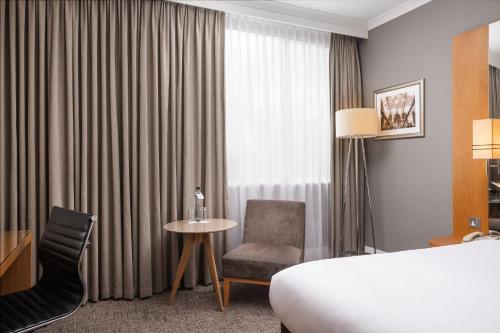 a hotel room with a bed and a chair and a table at Crowne Plaza London Ealing by IHG in London