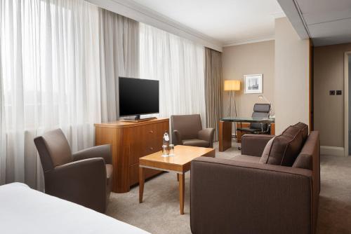a hotel room with a television and a couch and chairs at Crowne Plaza London Ealing by IHG in London