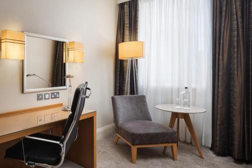 a room with a chair and a table and a mirror at Crowne Plaza London Ealing by IHG in London