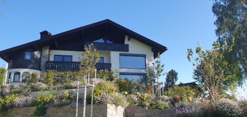 a house on a hill with flowers in front of it at Bergzauber Alpin Suites - Skipiste - Private Sauna in Bolsterlang