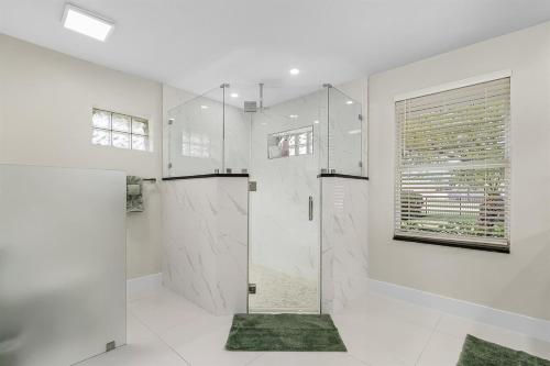 een witte badkamer met een douche en een glazen deur bij Lux 5BDR HUGE HTD Pool NR BEACH in Naples