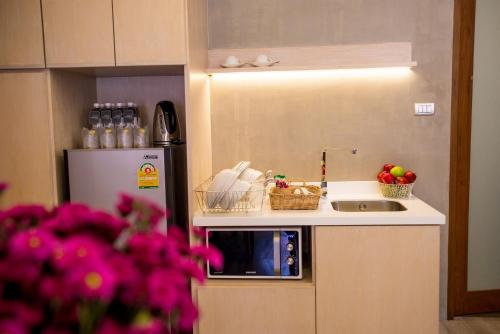a small kitchen with a sink and a refrigerator at Chu Hotel in Chiang Mai