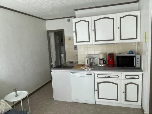 une cuisine avec des armoires blanches et un micro-ondes dans l'établissement Les Dunes, à Saint-Hilaire-de-Riez