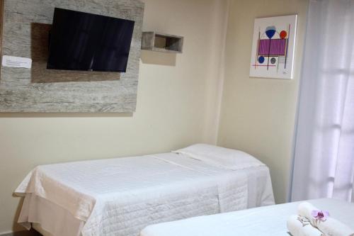 a room with two beds and a tv on the wall at Atobás in Arraial do Cabo