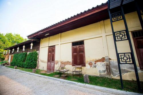 a building with two doors and a bench on the side at Chu Hotel in Chiang Mai