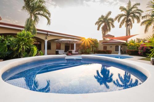 a swimming pool in front of a house with palm trees at Las Brisas Resort and Villas in Jacó