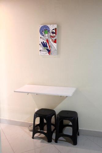 a white table with two stools under a painting at Atobás in Arraial do Cabo