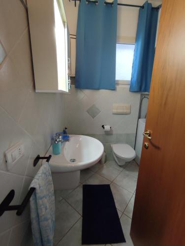 a bathroom with a sink and a toilet and blue curtains at Appartamento Meduse in Cala Gonone