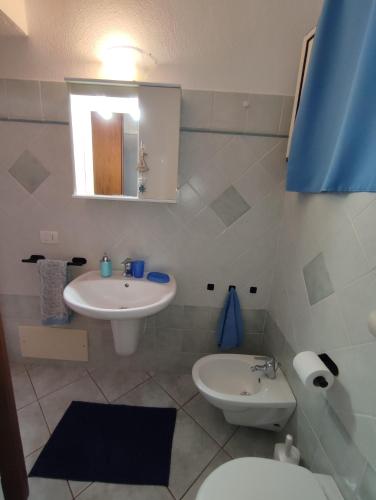 a bathroom with a sink and a toilet and a mirror at Appartamento Meduse in Cala Gonone