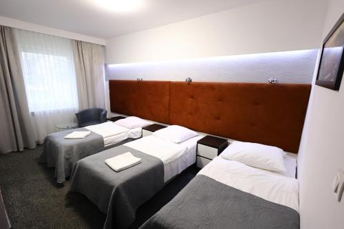 pokój hotelowy z 3 łóżkami i krzesłem w obiekcie Hotel Junior w Krakowie