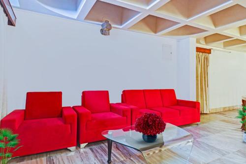 a living room with red chairs and a table at Super Hotel O Alpine Glow Crest in Hyderabad