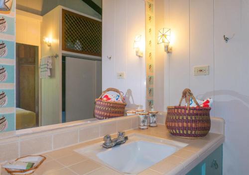 a bathroom with a sink and two baskets on the counter at Wainiha Beach Hale in Wainiha