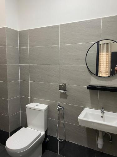 a bathroom with a toilet and a sink and a mirror at Desa Murni Homestay in Kuantan