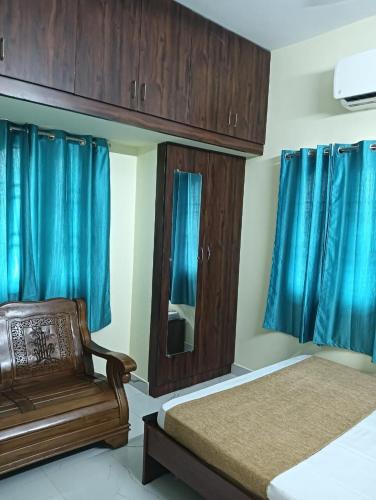 1 Schlafzimmer mit 2 Betten, einem Spiegel und blauen Vorhängen in der Unterkunft DwarakaSamudra Residency in Tiruvannāmalai