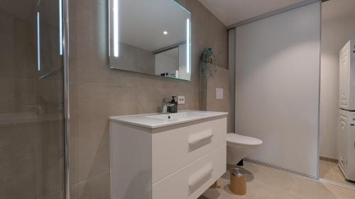 a bathroom with a sink and a mirror and a toilet at Åros Seaside Apartment with Pool, Jacuzzi & Sauna in Kristiansand